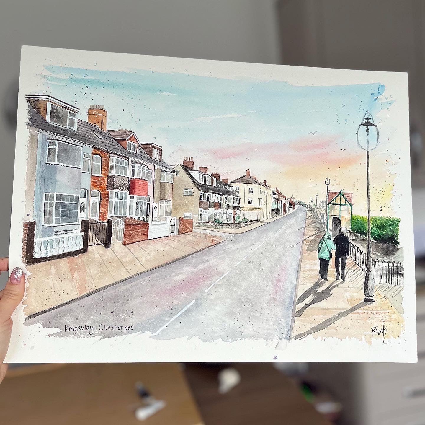 An original watercolour painting of the Kingsway, Cleethorpes, with a couple walking along. This original artwork was painted by local Cleethorpes artist, Eve Leoni Smith.