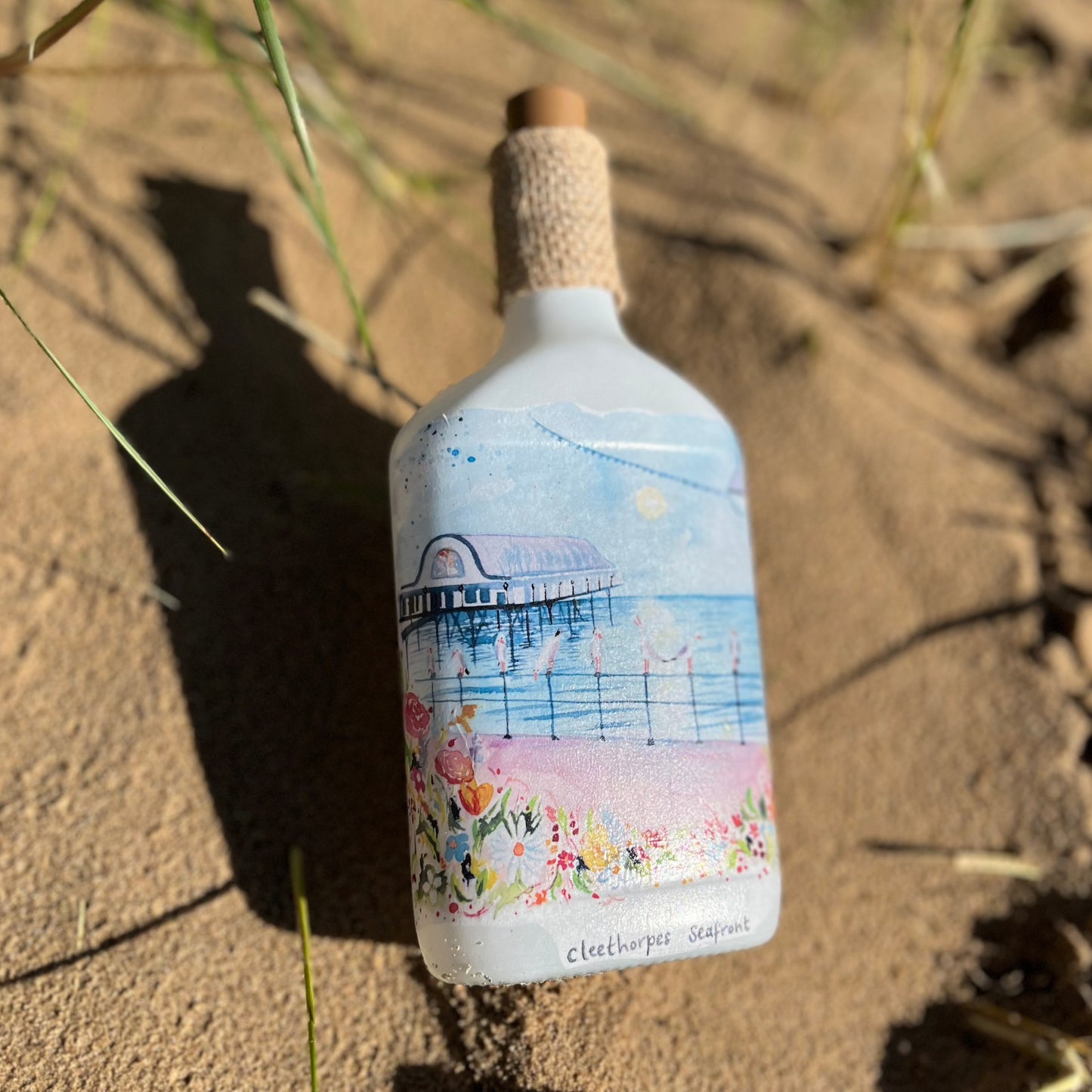 A decoupaged bottle featuring a watercolour illustration of the Cleethorpes Seafront by local artists Eve Leoni Art and Jollypotz.