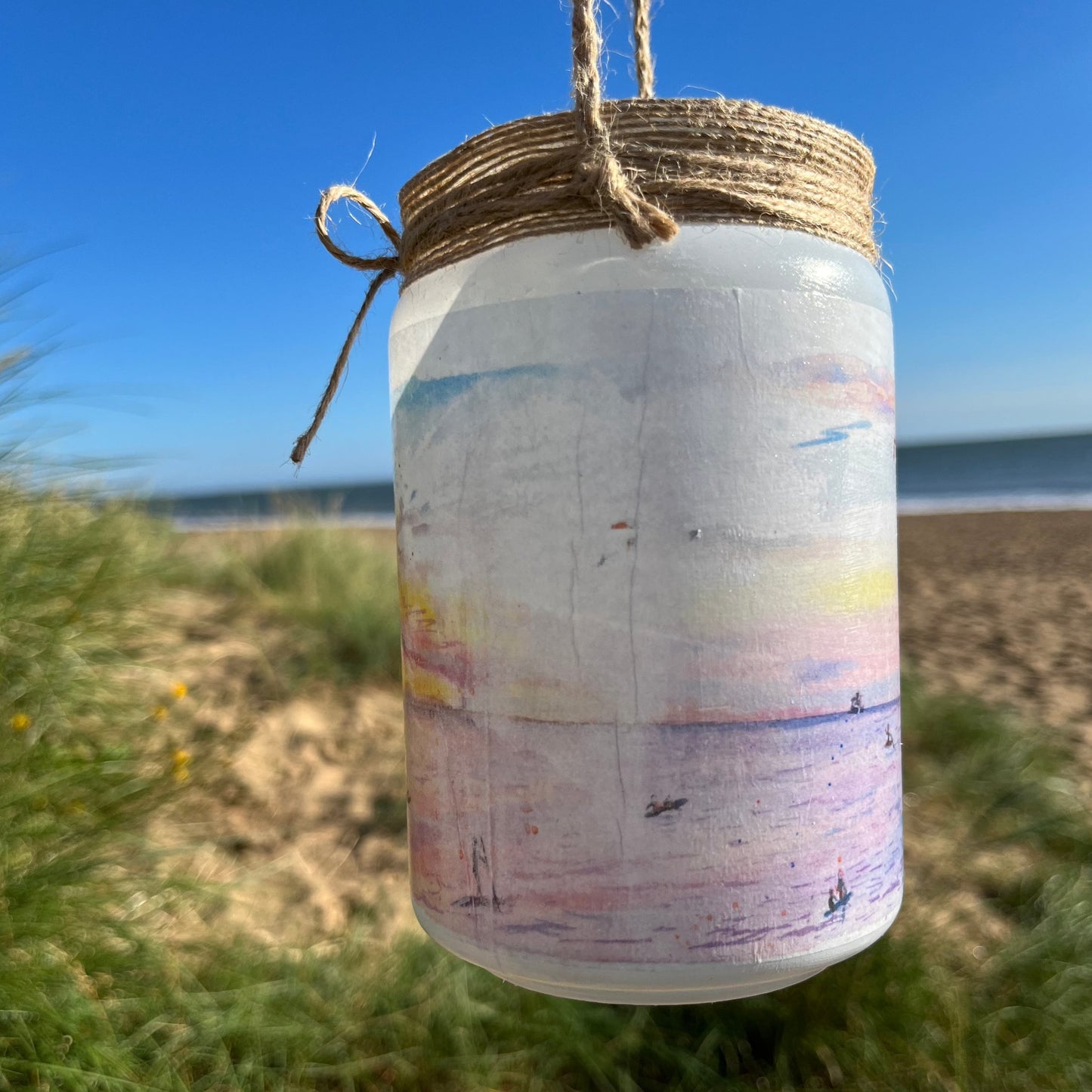 A firefly jar decoupaged with watercolour artwork of Humberston Fitties Beach at sunset, painted by Eve Leoni Smith and decorated by Jollypotz.