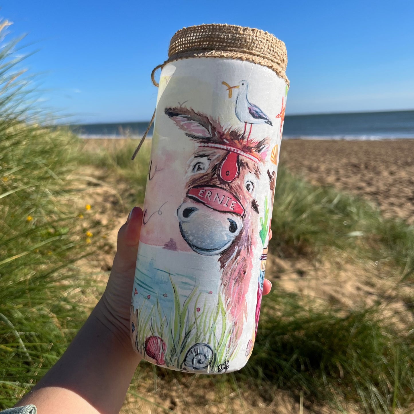 A decoupaged jar on Cleethorpes beach featuring watercolour artwork of a donkey by local artist, Eve Leoni Smith.