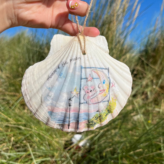 A decoupaged shell on Cleethorpes beach, featuring watercolour artwork of the Mouse and the Moon by Eve Leoni Smith and Jollypotz.
