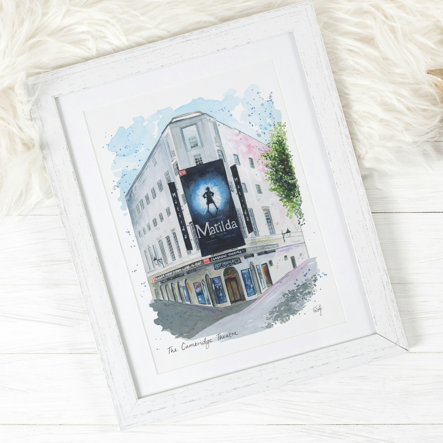 An original watercolour painting of the Cambridge Theatre at Seven Dials in London's West End, featuring Matilda the Musical. Painted by local artist, Eve Leoni Smith.