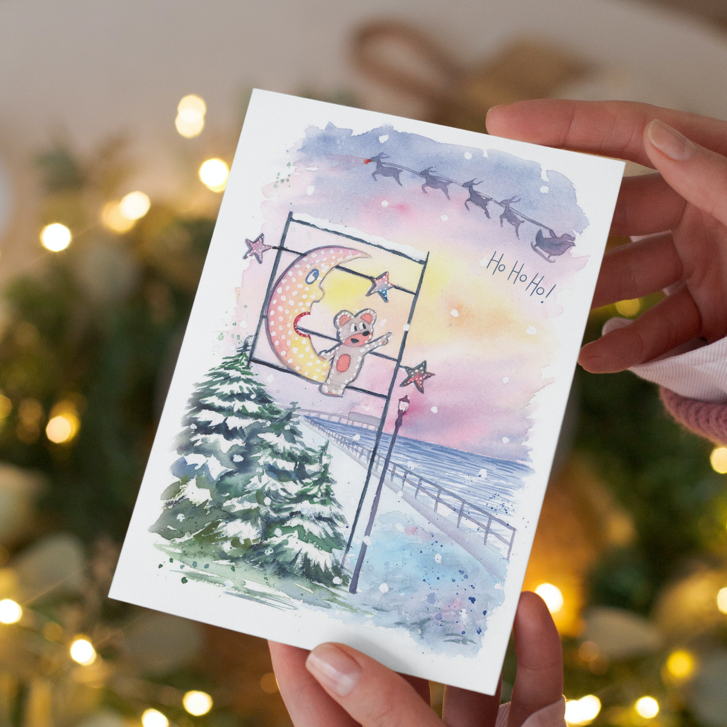 A watercolour illustration of the Mouse and the Moon watching Santa and his sleigh fly over the Cleethorpes Pier at Christmas time. Painted by Grimsby artist, Eve Leoni Smith.
