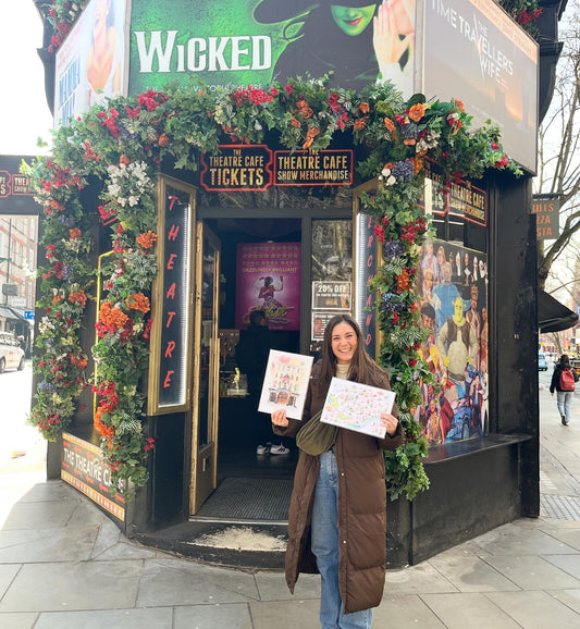 London based-artist and performer, Eve Leoni Smith, stood outside the Theatre Cafe Gift Shop whilst holding up watercolour paintings down Shaftesbury Avenue in London's West End.