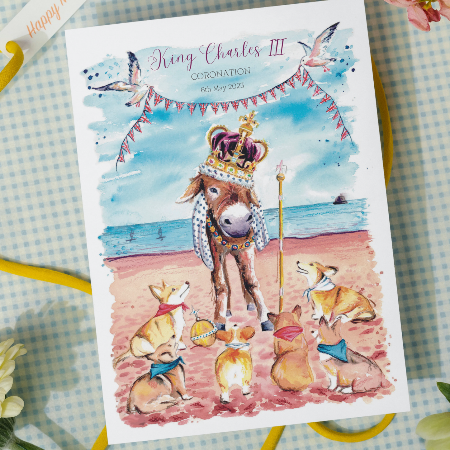 A limited edition signed print to commemorate King Charles III Coronation, featuring a donkey in the crown jewels on Cleethorpes beach surrounded by some royal corgis. Painted in watercolours by Eve Leoni Smith.