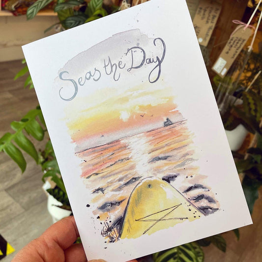 A greetings card featuring a watercolour illustration of the sea at Cleethorpes beach from a paddleboarder's view. Caption says, 'Seas the Day.'