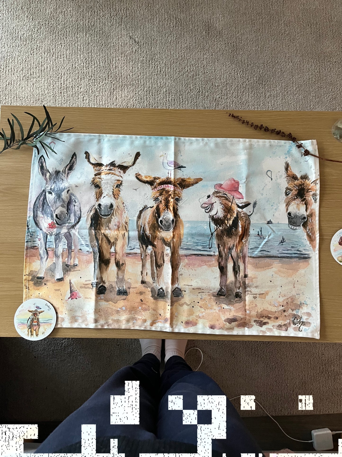 An organic tea towel featuring original watercolour artwork of the Cleethorpes donkeys by local Grimsby artist, Eve Leoni Smith.