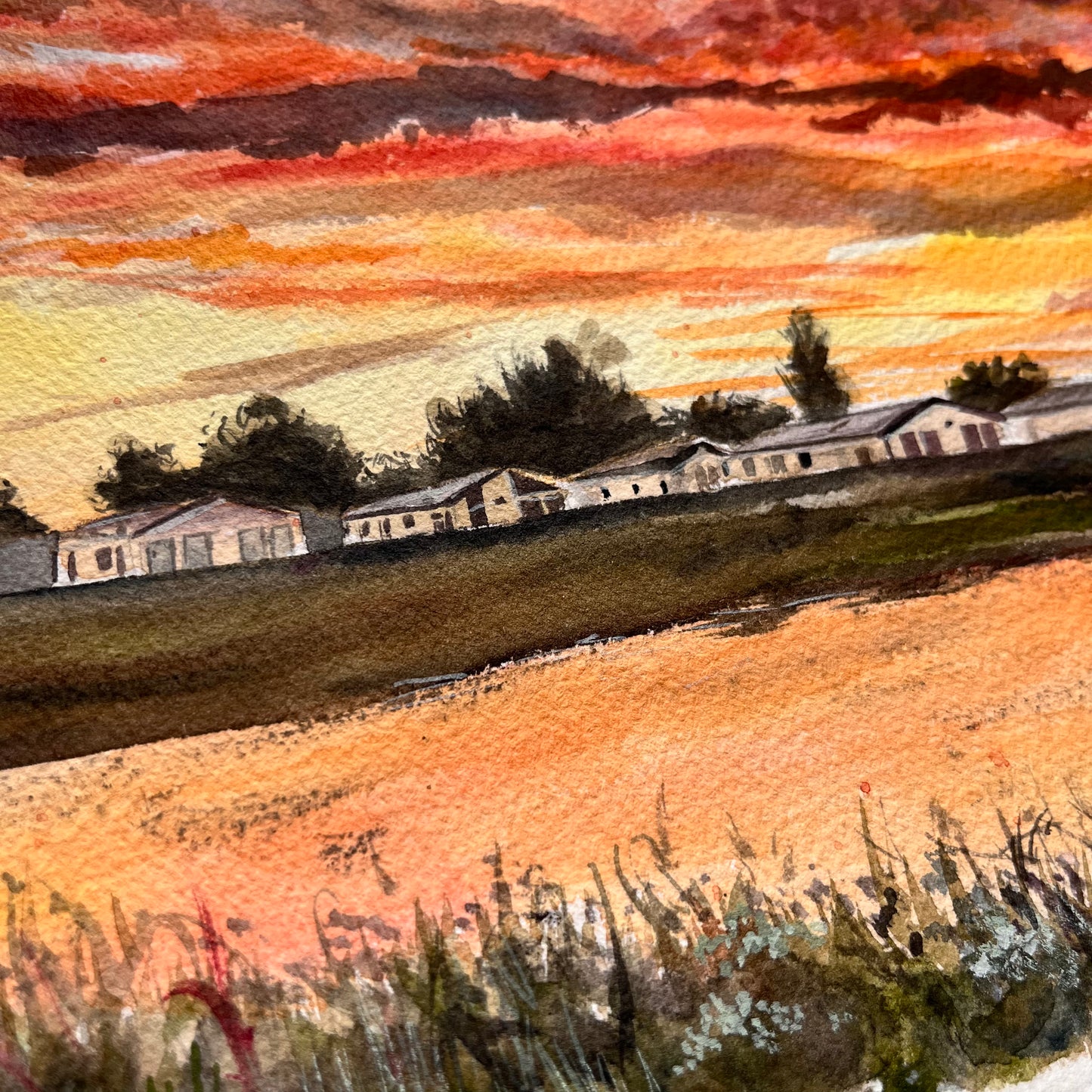 A close-up shot of this original watercolour painting of the caravans in Humberston under a bright orange sunset, painted by Grimsby artist, Eve Leoni Art.