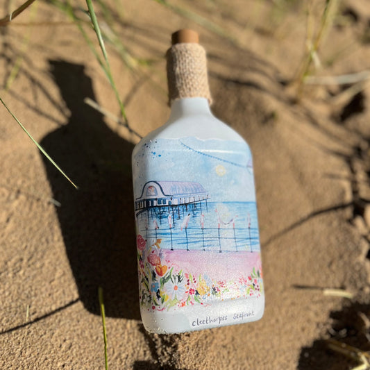 A decoupaged bottle featuring a watercolour illustration of the Cleethorpes Seafront by local artists Eve Leoni Art and Jollypotz. 