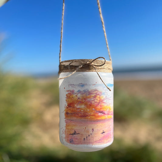A firefly jar decoupaged with watercolour artwork of Humberston Fitties Beach at sunset, painted by Eve Leoni Smith and decorated by Jollypotz. 
