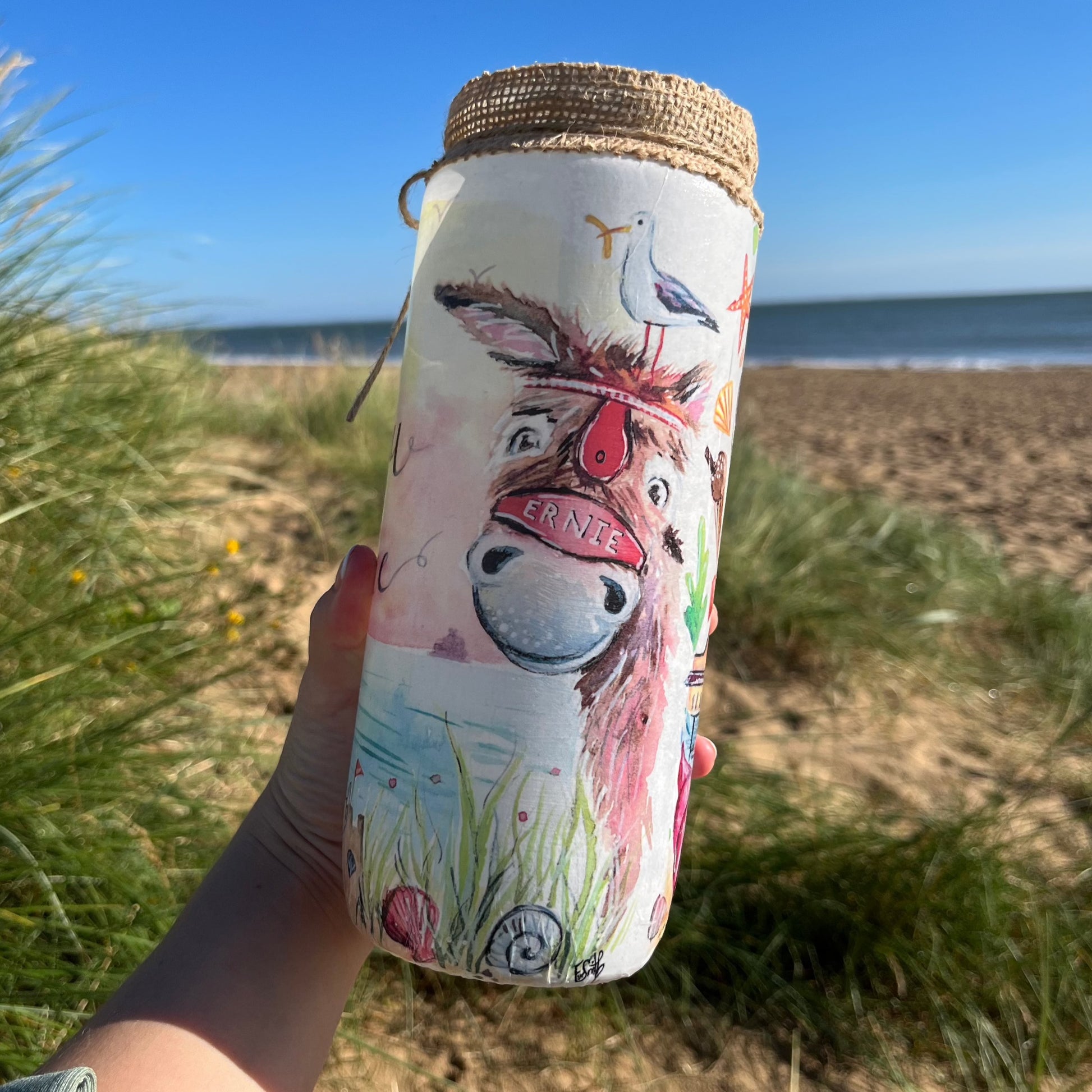 A decoupaged jar on Cleethorpes beach featuring watercolour artwork of a donkey by local artist, Eve Leoni Smith. 