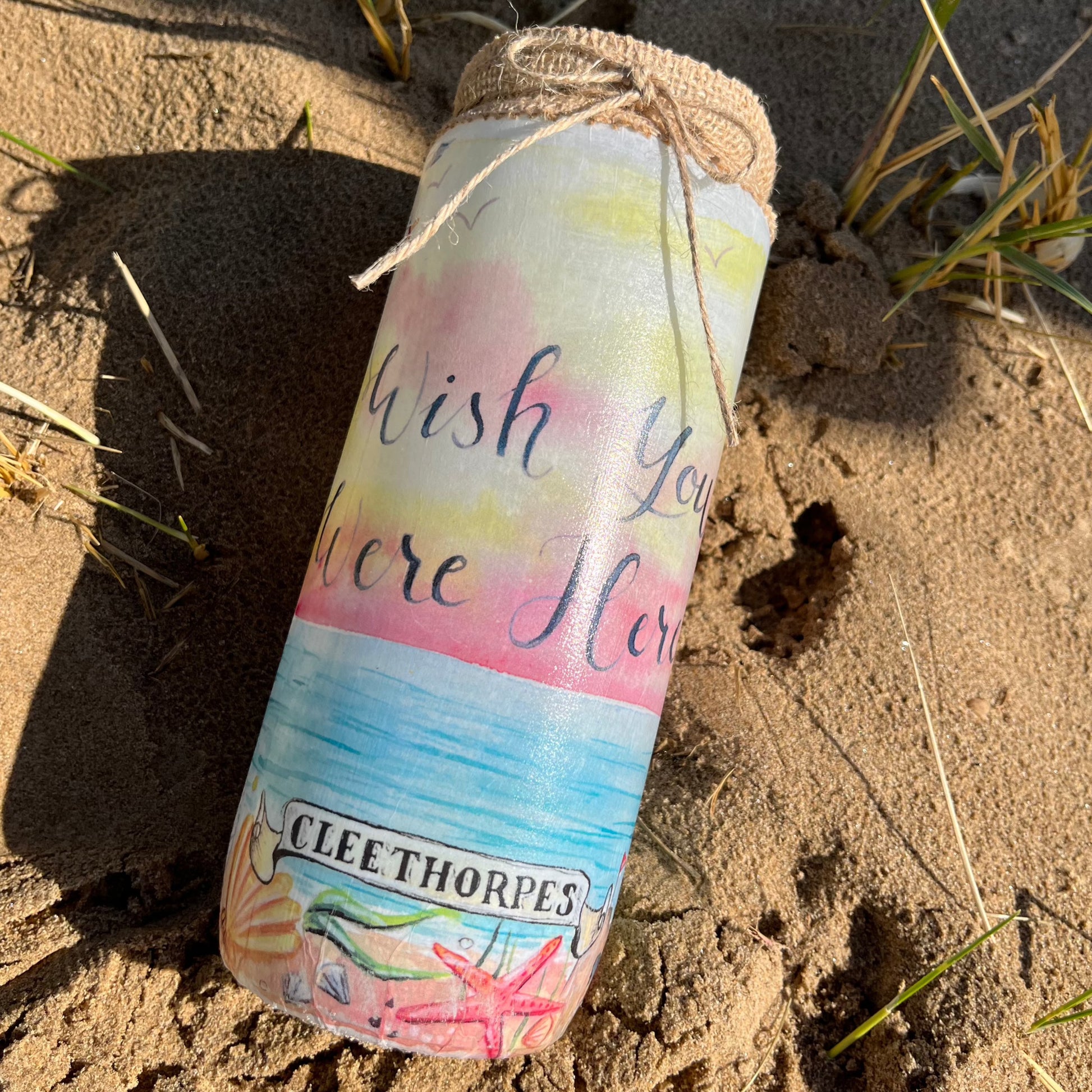 A decoupaged jar on Cleethorpes beach featuring watercolour artwork by local artist, Eve Leoni Smith. 