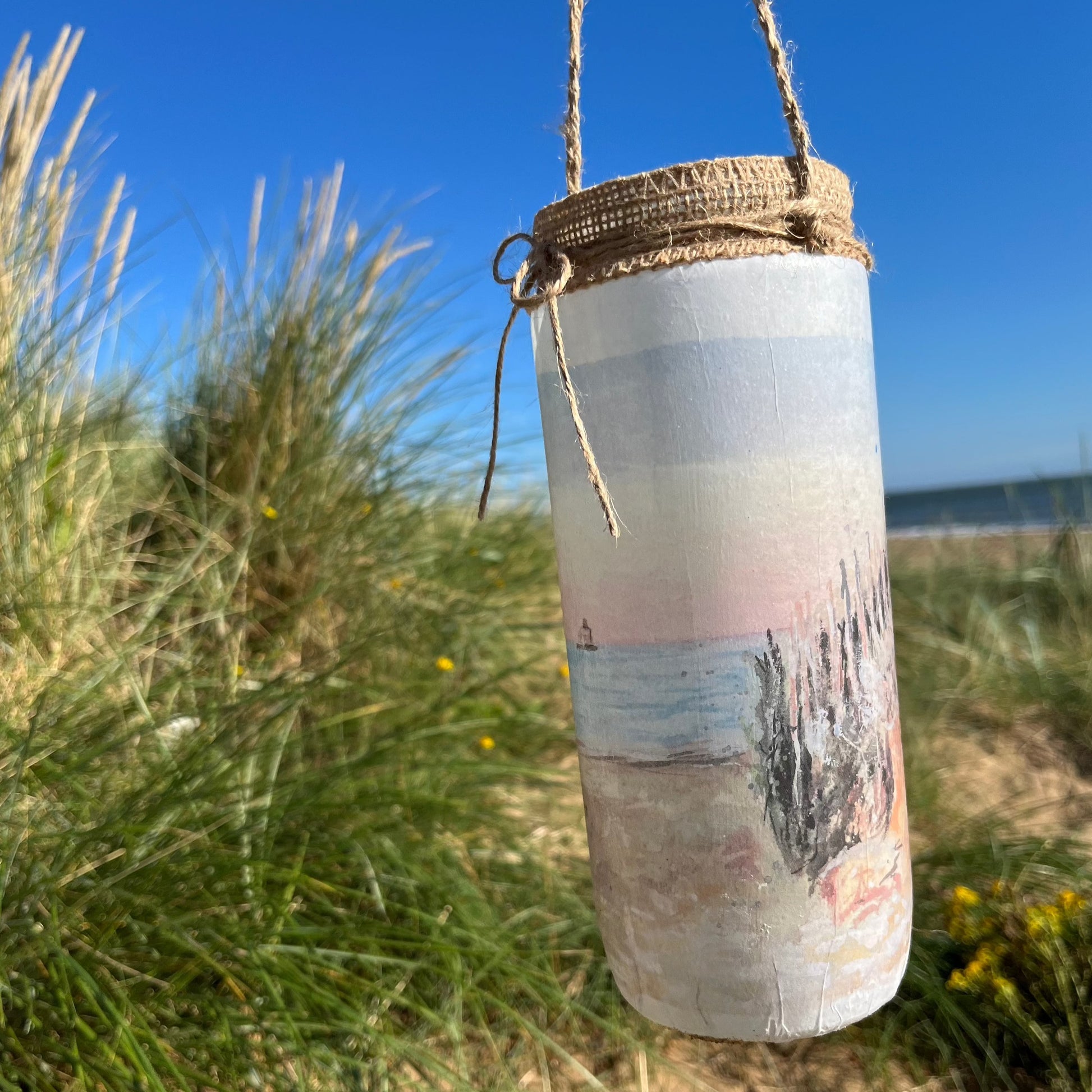 A decoupaged jar on Cleethorpes beach, featuring watercolour artwork of the Humberston Fitties by Eve Leoni Smith and Jollypotz.