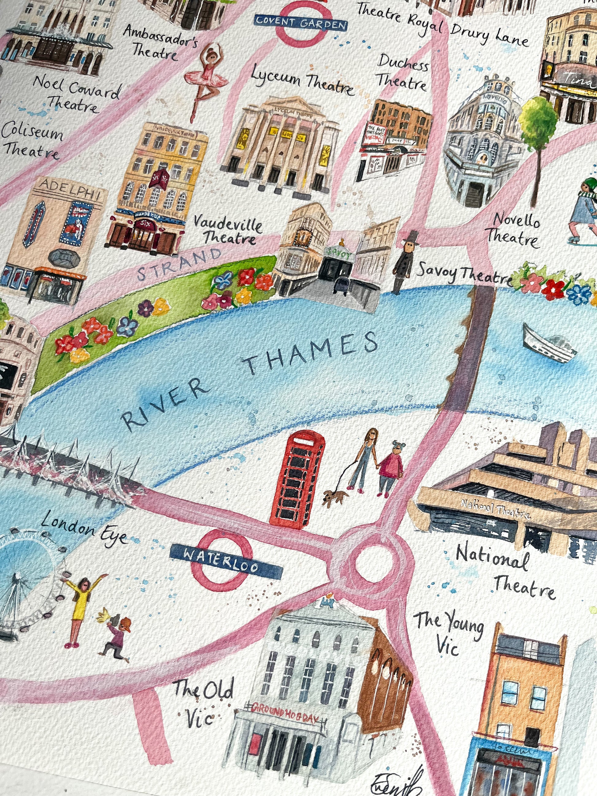 A close up photo of an illustrated West End map by Eve Leoni Art, featuring watercolour paintings of the Vaudeville Theatre, Savoy Theatre, Novello Theatre and National Theatre.
