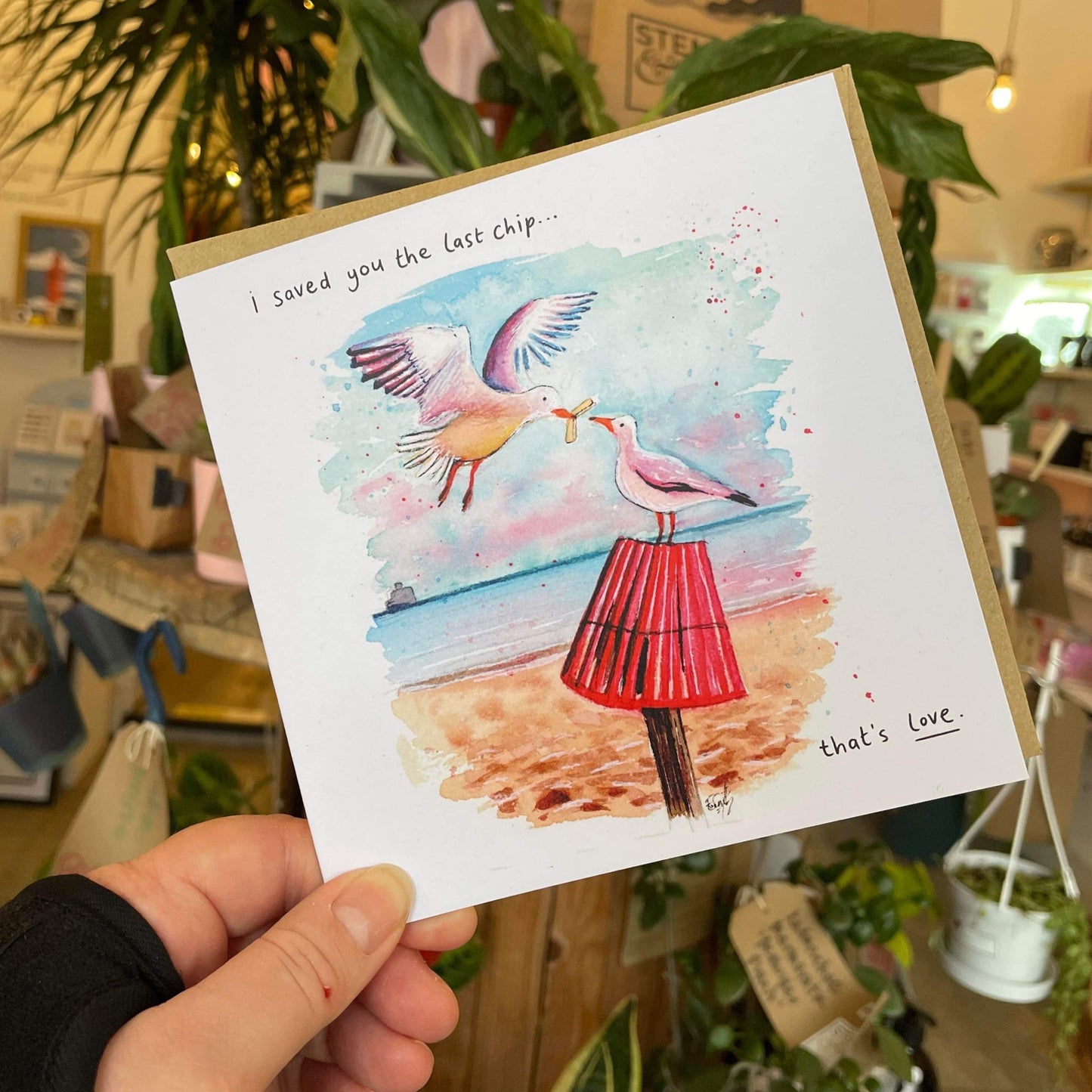 A recycled greetings card featuring a watercolour illustration of two seagulls on Cleethorpes beach exchanging a chip; painted by Cleethorpes artist, Eve Leoni Smith.