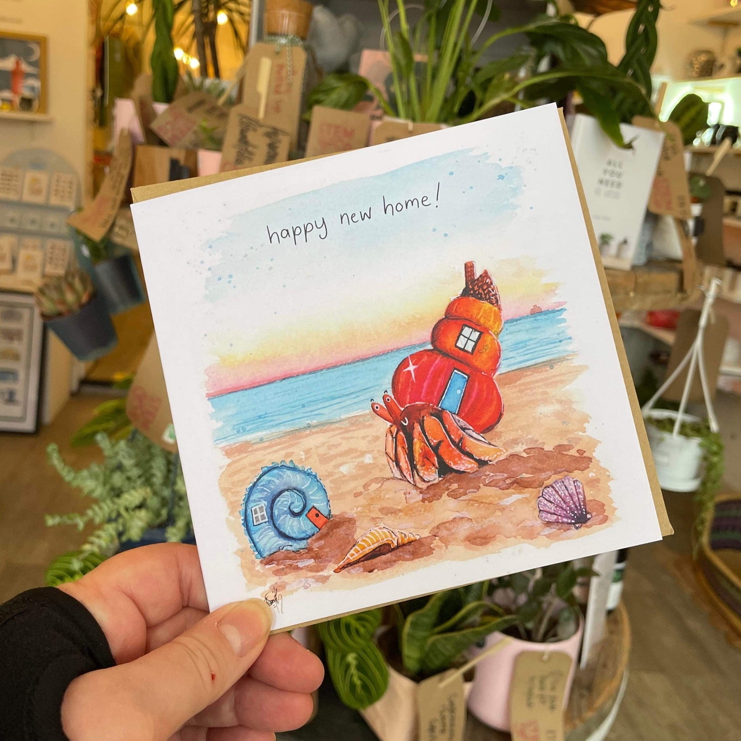 A recycled greetings card designed and painted by Cleethorpes artist, Eve Leoni Smith, featuring a hermit crab and his new shell home on Cleethorpes beach.
