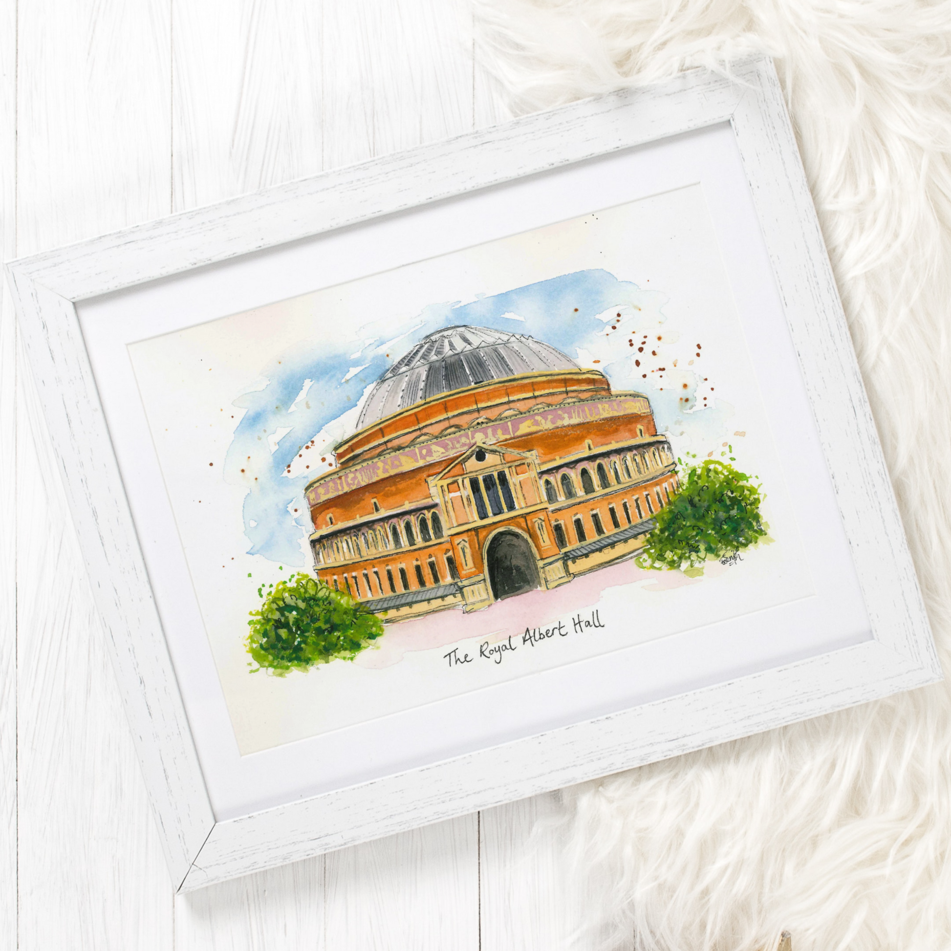 A framed watercolour illustration of the Royal Albert Hall in London, by local artist and performer, Eve Leoni Smith.