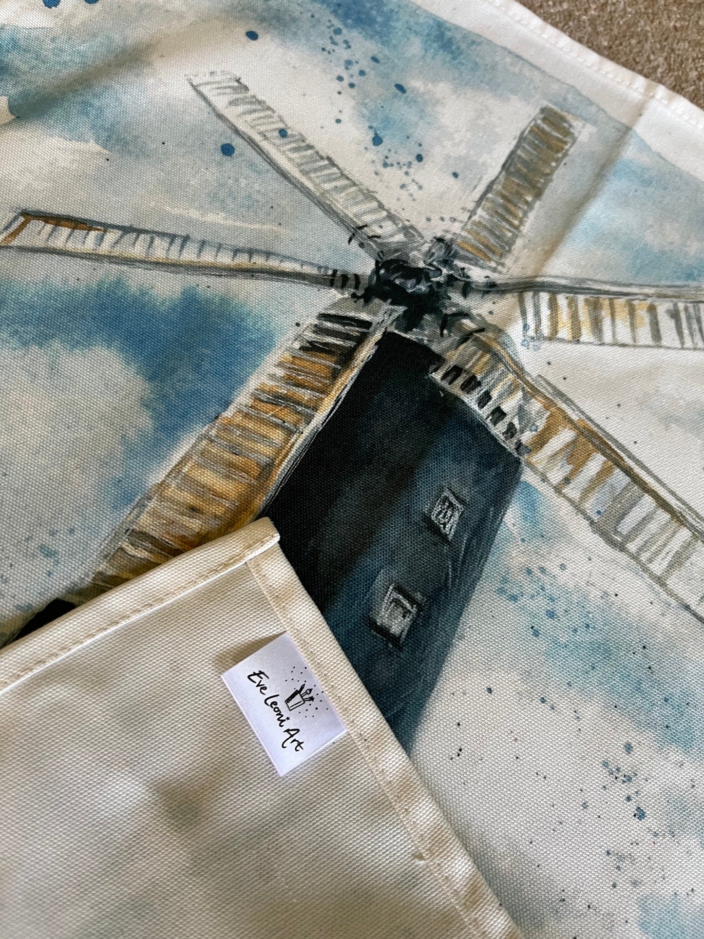 A close up image of an organic tea towel featuring artwork of the Waltham Windmill by Eve Leoni Art.